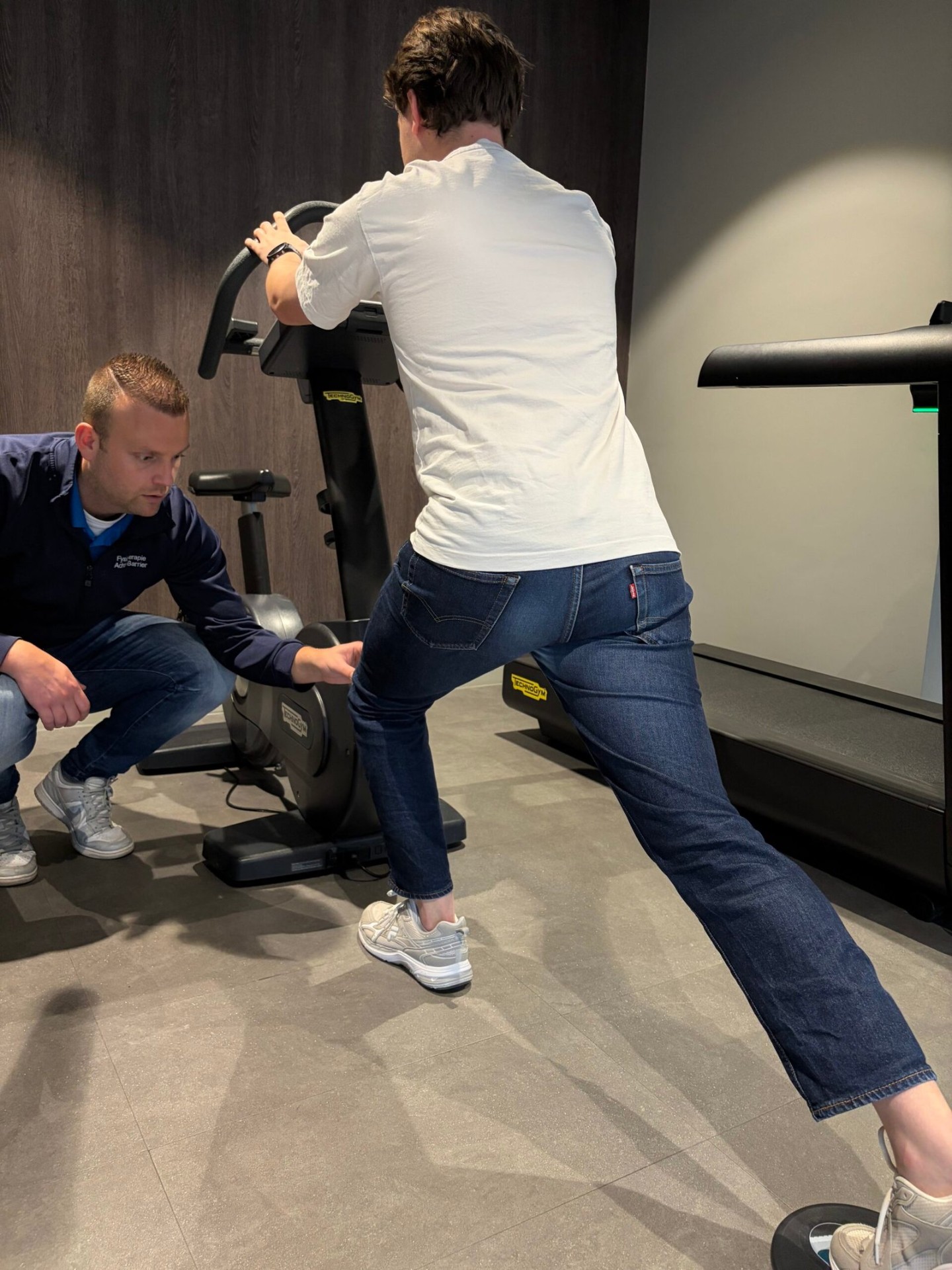Patiënt doet krachtoefening op trainingsmachine onder begeleiding van fysiotherapeut bij Fysiotherapie Strijp-S