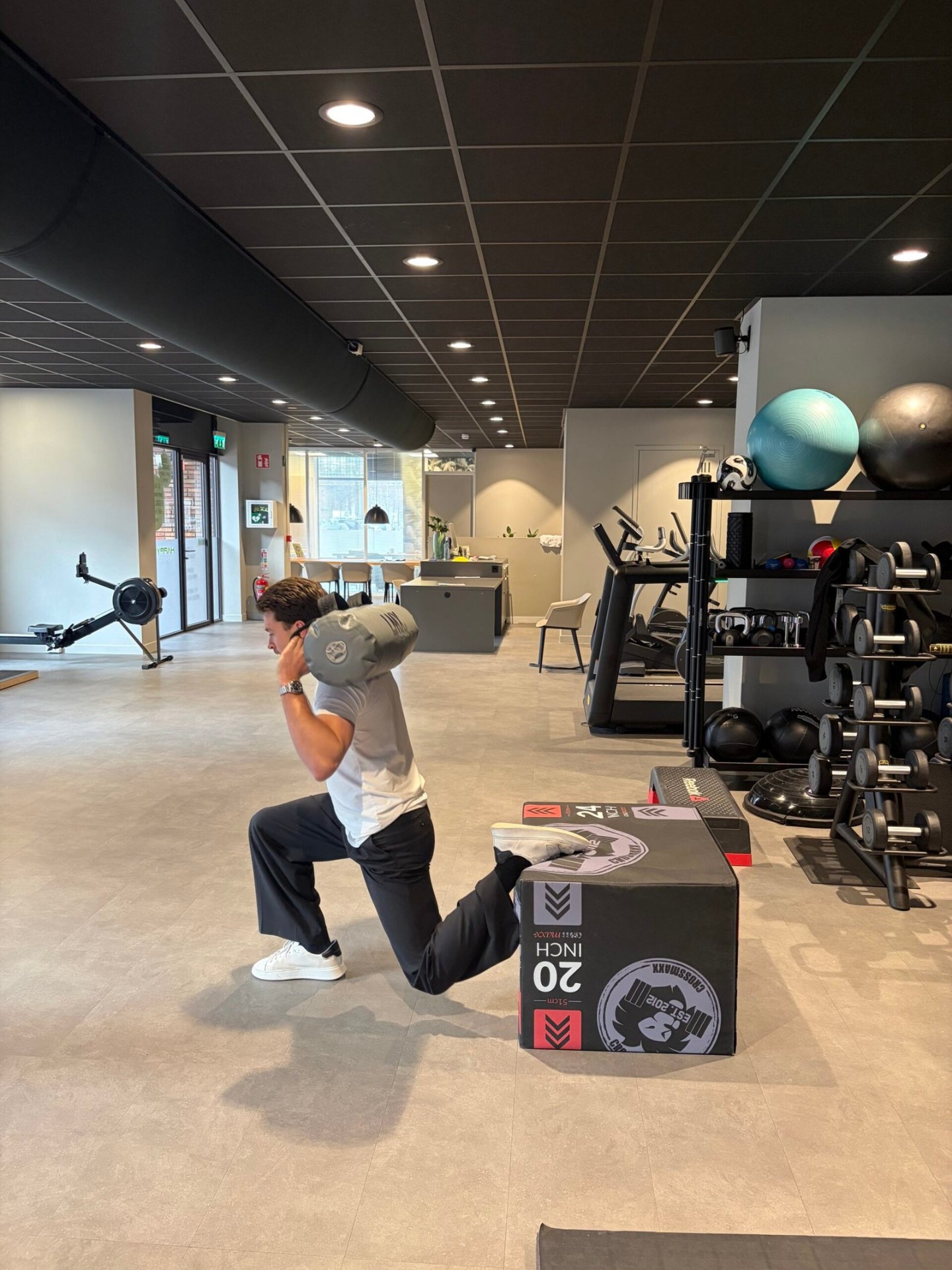 Patiënt voert lunge-oefening uit met sandbag tijdens sportfysiotherapie bij Fysiotherapie Strijp-S Eindhoven