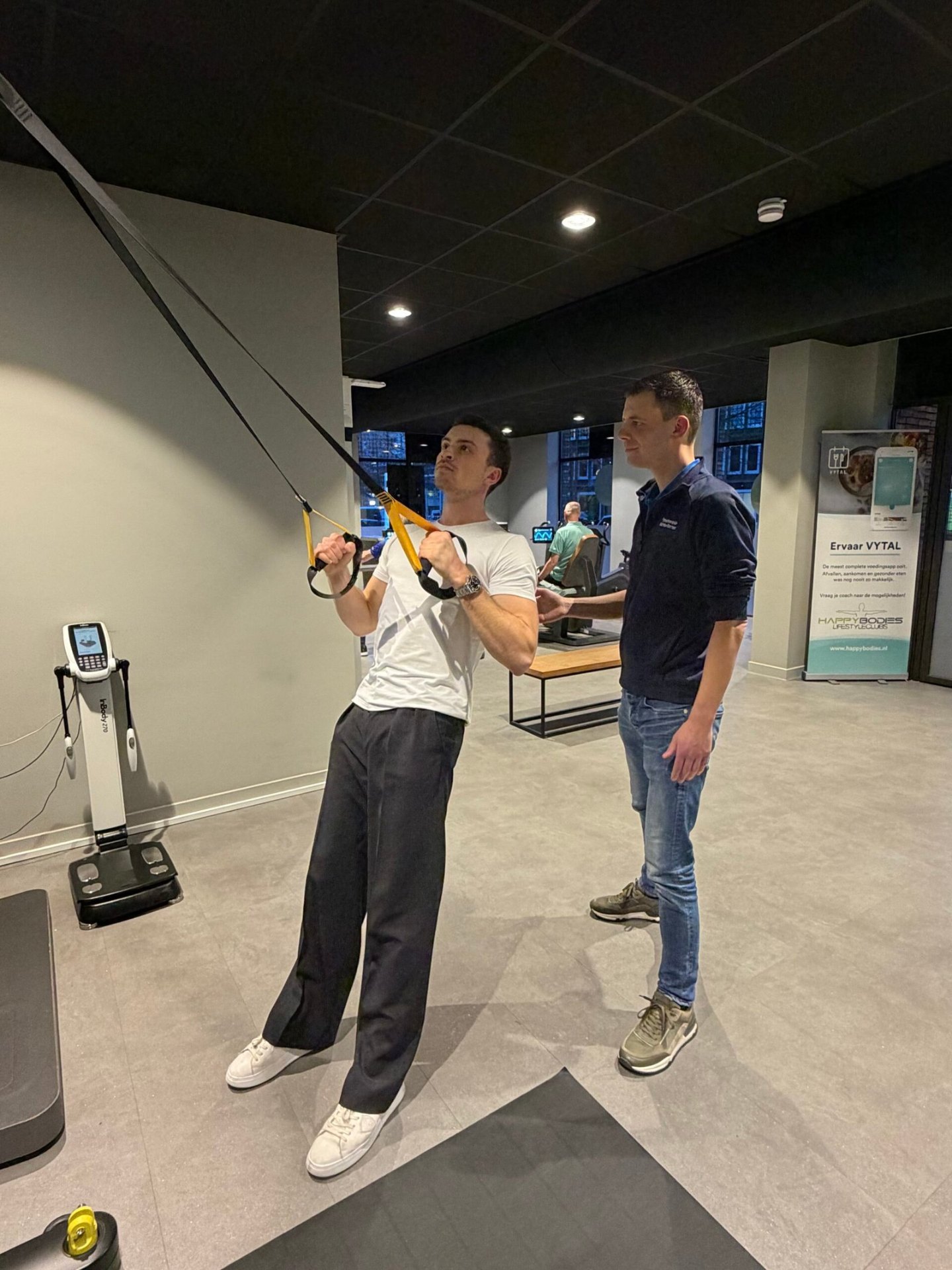 Patiënt traint met TRX-banden onder begeleiding van fysiotherapeut tijdens revalidatie bij Fysiotherapie Strijp-S